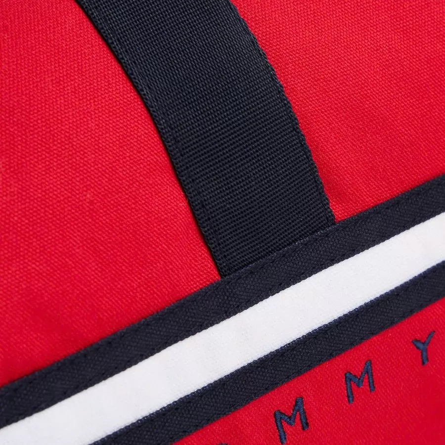 Bé trai tự tin xách chiếc túi duffle trẻ em Tommy Hilfiger logo sọc cờ, lý tưởng cho chuyến đi học hay dã ngoại cuối tuần.